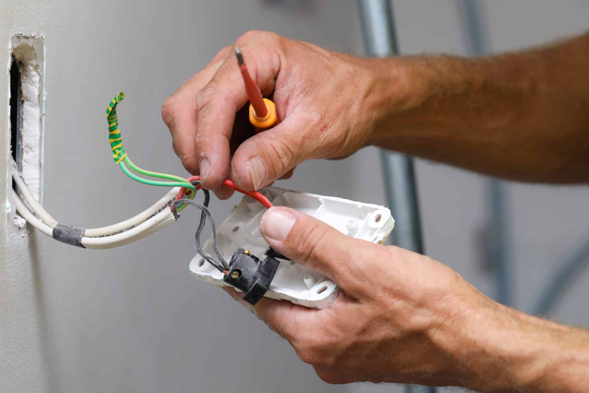 A close up of an electrician working on a light switch